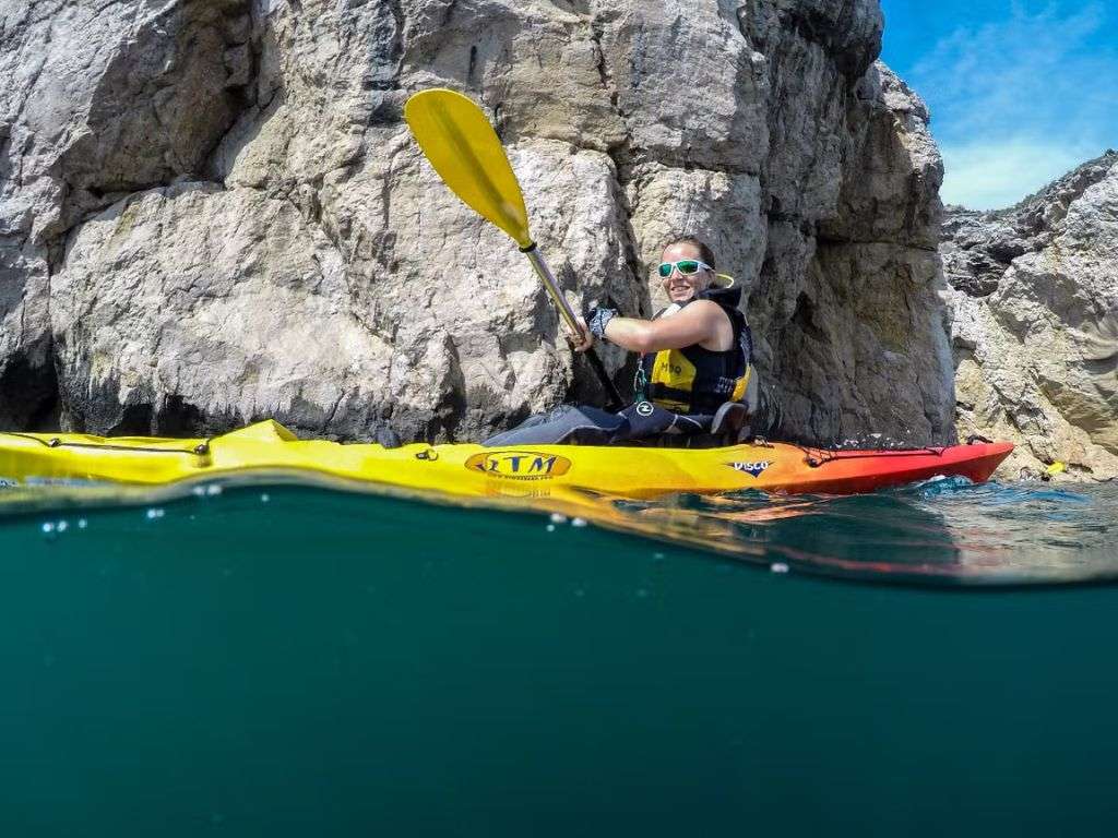 一名妇女站在埃尔埃斯塔蒂特(El Estartit)烧烤海滩上一块被侵蚀的岩石旁划船。.