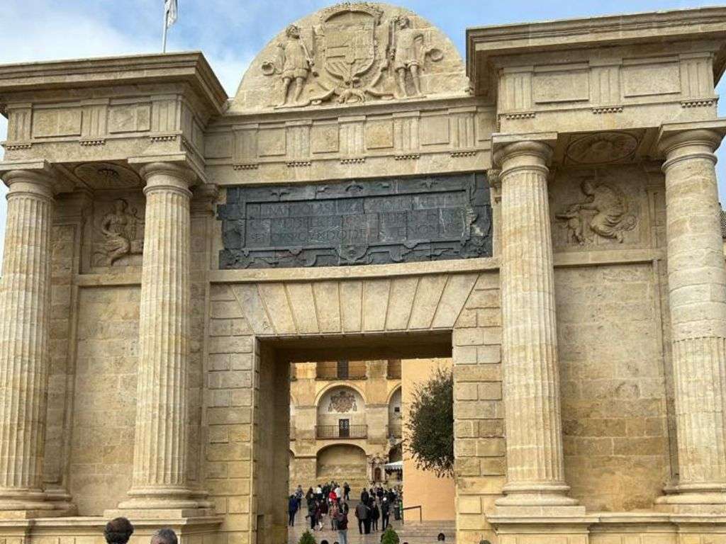 Foto de la entrada de la Mezquita con su estructura decorada en su estilo artístico, donde se encuentra gente pasando por ella.
