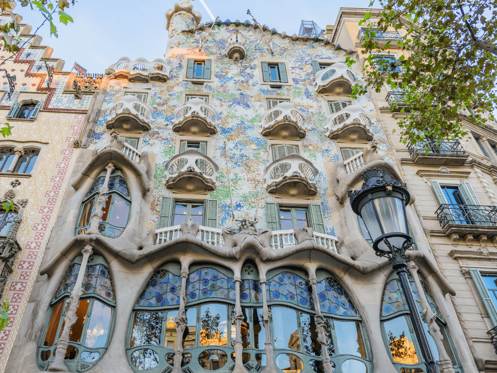 Vista frontal de la Casa Batlló en Barcelona, obra de Antoni Gaudí, destacando su fachada ondulada y colorida con mosaicos y formas inspiradas en la naturaleza.