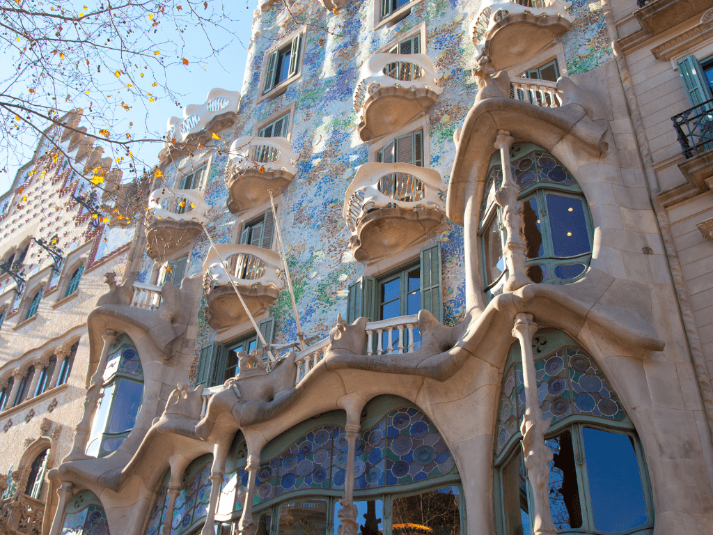 Vista detallada de las ventanas de la Casa Batlló, mostrando su diseño único con marcos ondulados y vidrieras de colores, reflejando el estilo modernista característico de Antoni Gaudí.