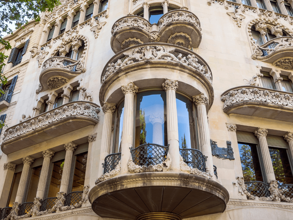 Vista de la fachada de la Casa Lleó i Morera en Barcelona, destacando su rica decoración modernista con esculturas, mosaicos y detalles arquitectónicos intrincados, representativa del modernismo catalán