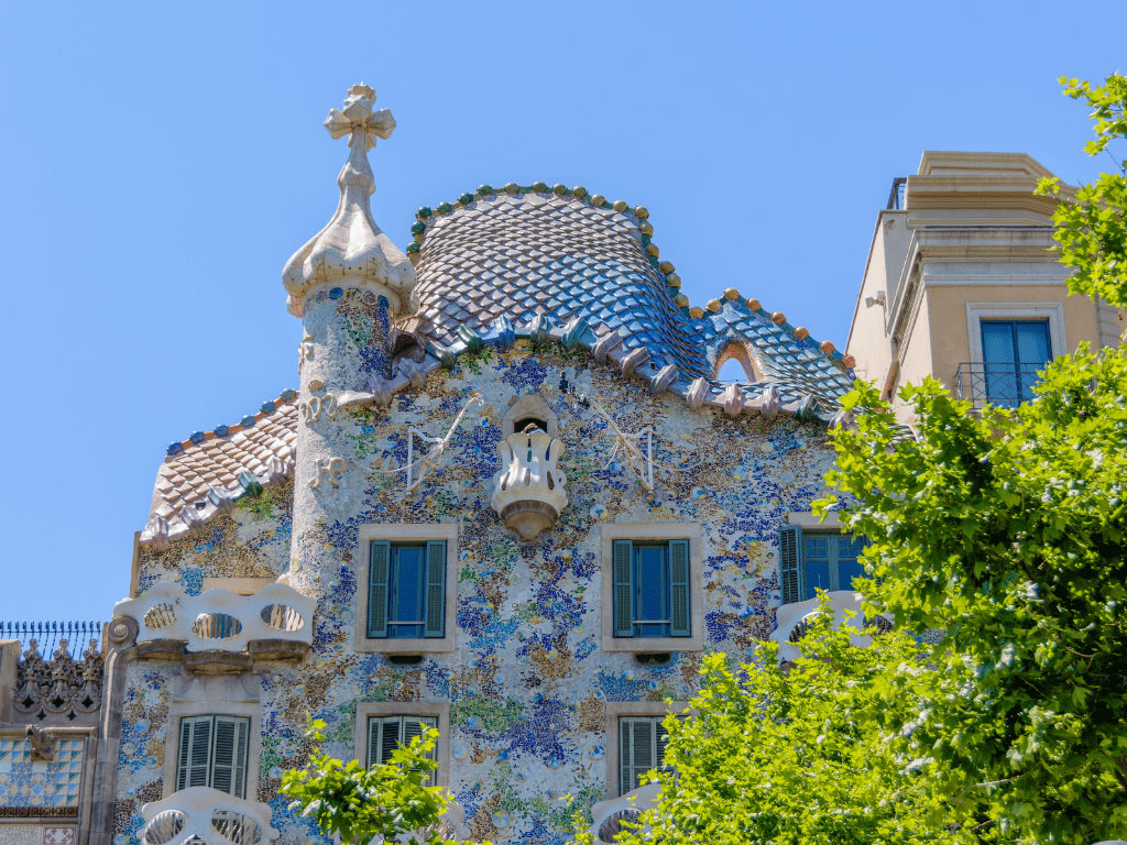 Vista detallada del colorido tejado de la Casa Batlló en Barcelona, diseñado por Antoni Gaudí, que se inspira en las formas de la naturaleza con azulejos que simulan las escamas de un dragón.