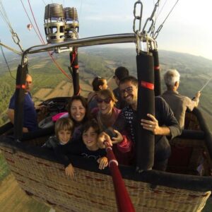 Una familia disfrutando de un emocionante vuelo en globo aerostático sobre el pintoresco paisaje del Empordà, Girona, con vistas panorámicas del entorno natural y cultural.