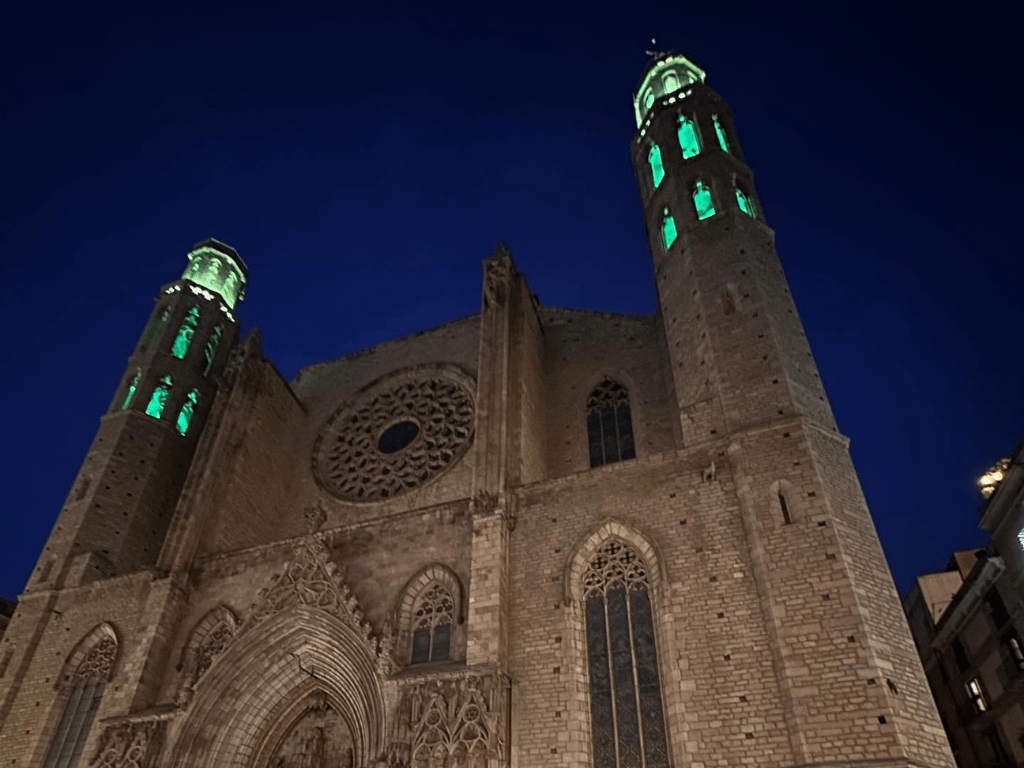 Vista nocturna de Santa Maria del Mar iluminada, destacando su imponente fachada gótica y las torres contra el cielo oscuro.